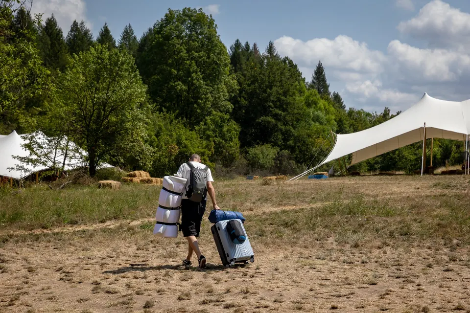 A festival-goer carrying a sleeping mat and suitcase into the camp