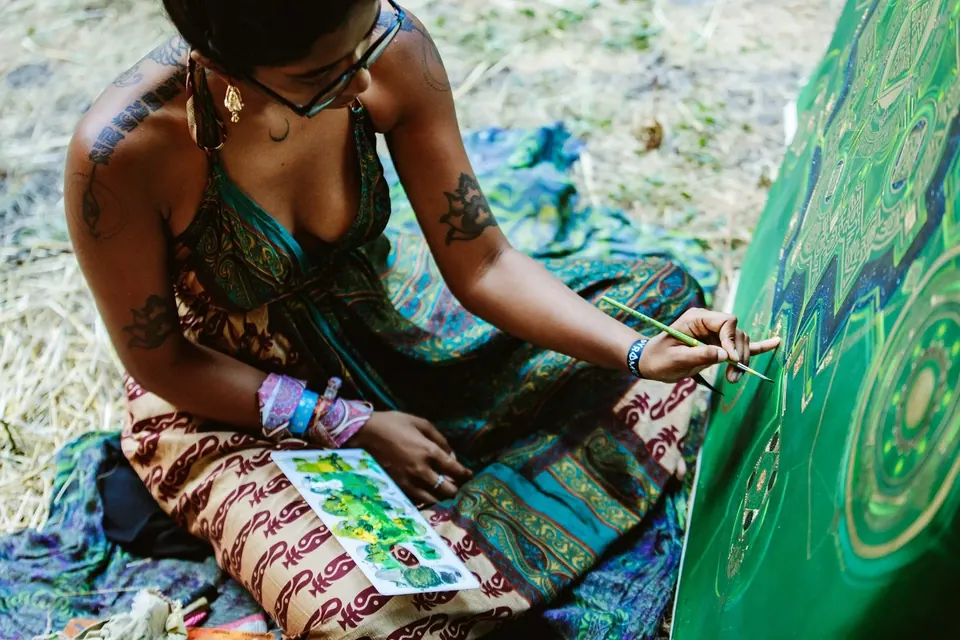 An artist painting a large canvas on the grass