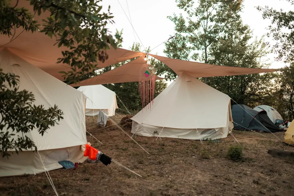 Pitched bell tents in the shade of the tipi camp
