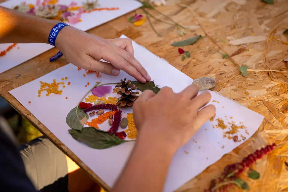 Hands pressing flowers onto paper at a workshop