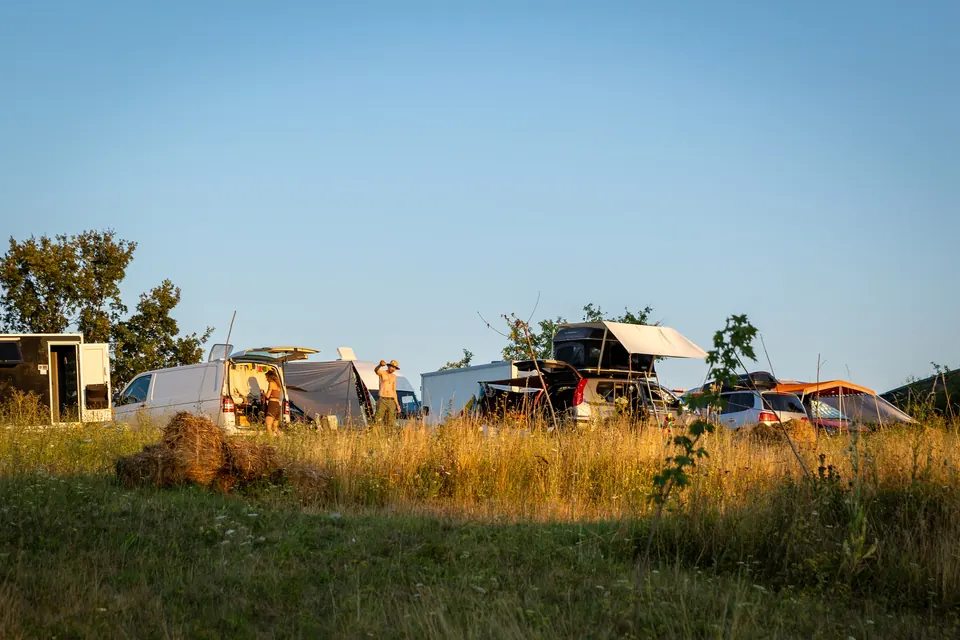 Vans, a roof tent and awnings in the camper area at golden hour