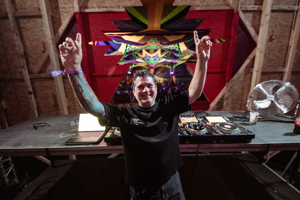 A DJ celebrating with both arms up in the booth
