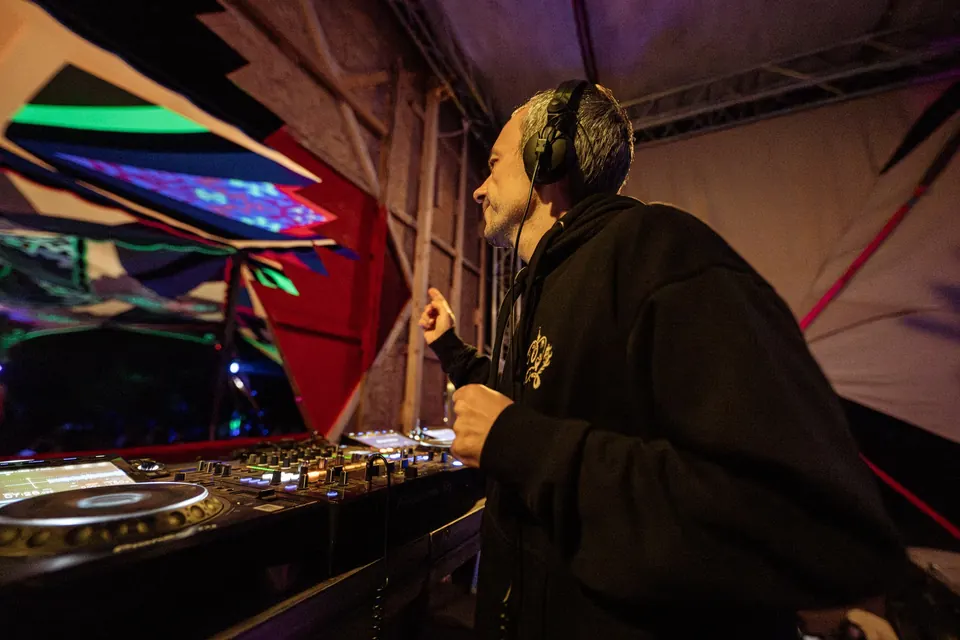 A DJ with headphones in the UV-lit booth