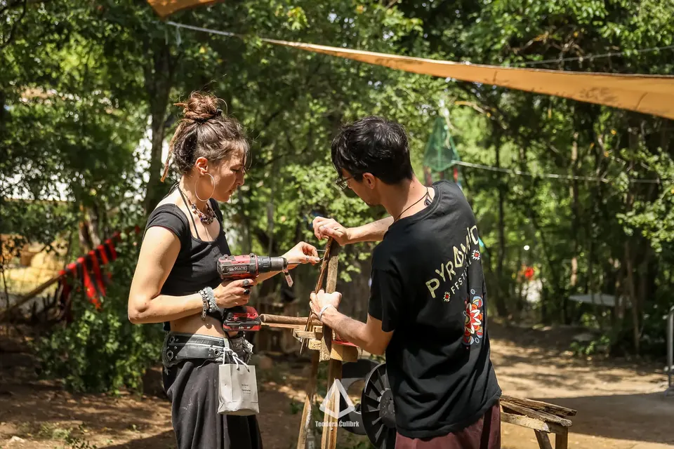 Dvoje volontera zajedno buše i sklapaju drvenu konstrukciju u Pyramid Eco Village.