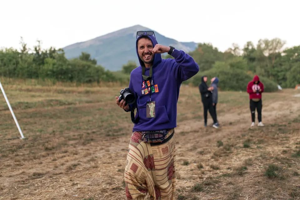 A smiling festival-goer in a hoodie on the meadow below Rtanj