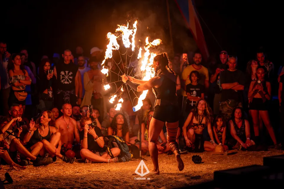 A fire dancer performing for a seated crowd at night