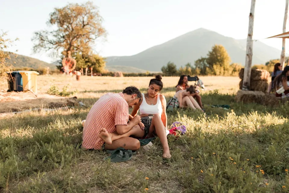 Friends sitting on the meadow facing Rtanj