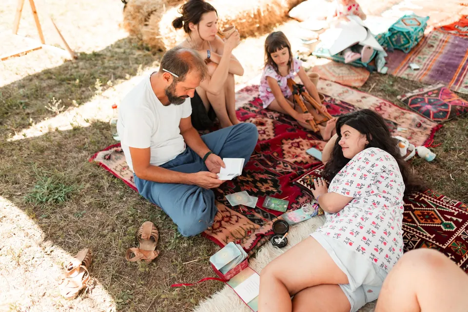 A facilitator holding a one-on-one reading on rugs under the trees