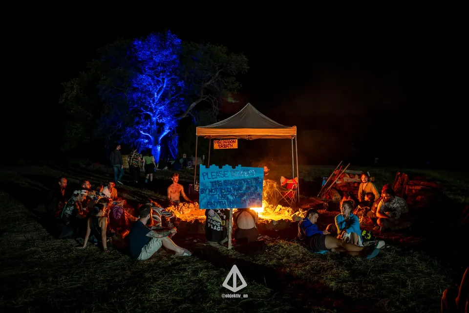 The camp at night under a blue-lit tree