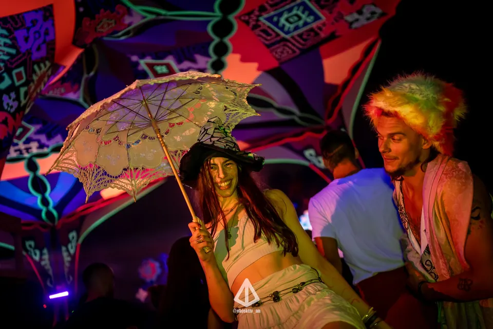 Two festival-goers with a lace umbrella under UV decor