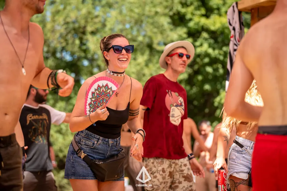 Festival-goers in sunglasses and hats dancing in the sun
