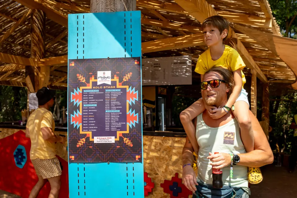 A father and child next to the KOLO stage timetable board
