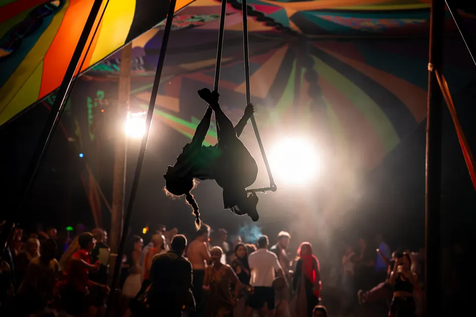 An aerial hoop acrobat above the crowd in the tent