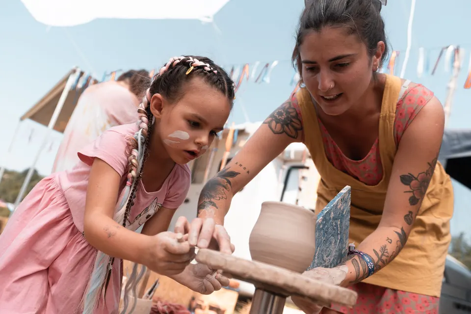 A potter shows a child how to shape clay at the Bazaar