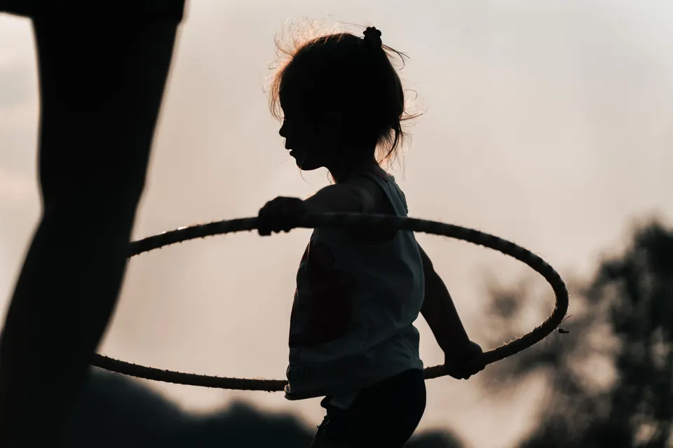 A child with a hula hoop in silhouette