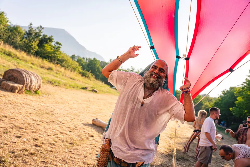 A man dances with Rtanj behind him