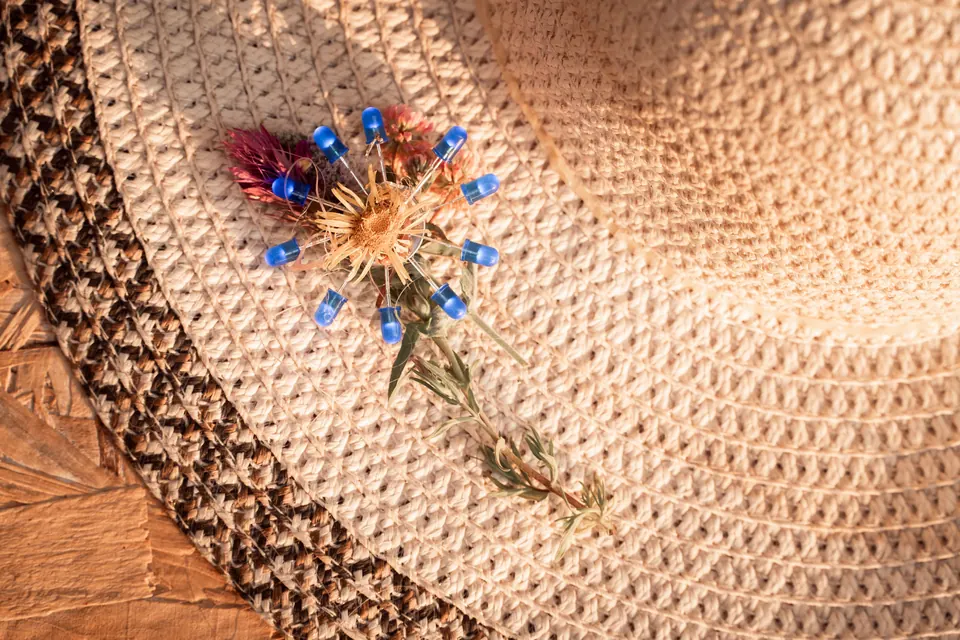 A dried flower pinned to a straw hat