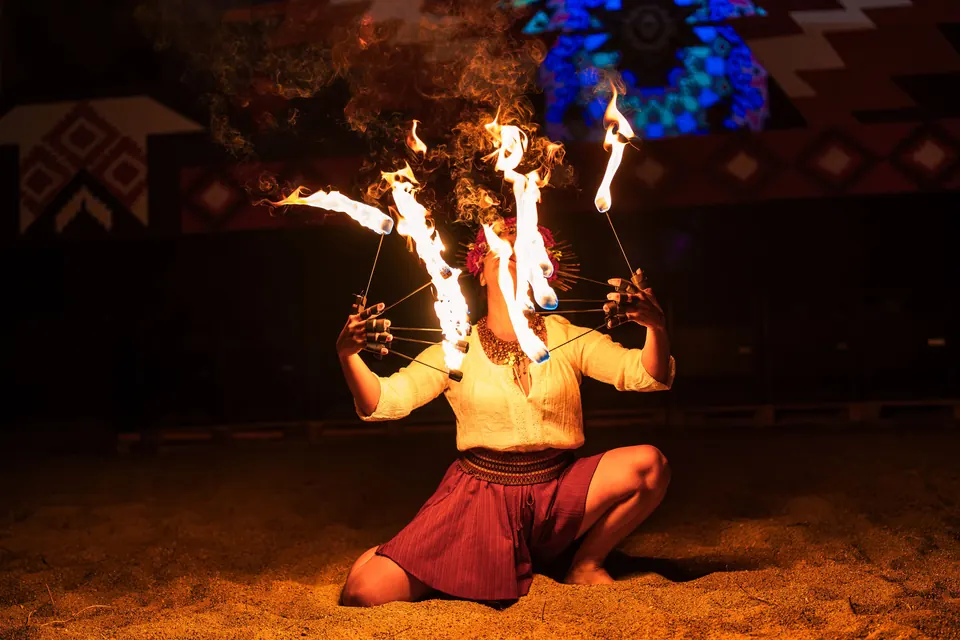 A kneeling dancer with fire fans