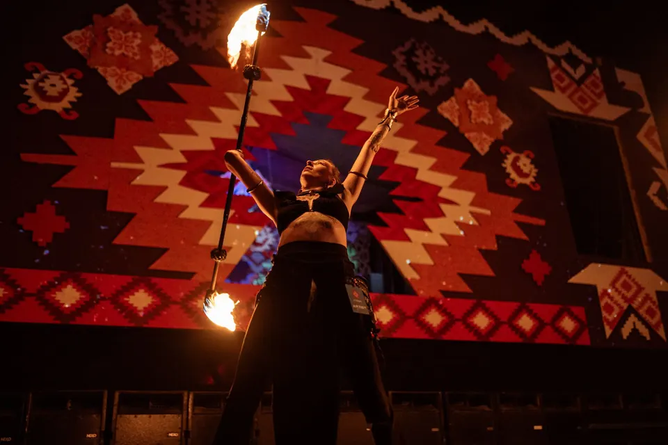 A fire staff in front of the ćilim backdrop