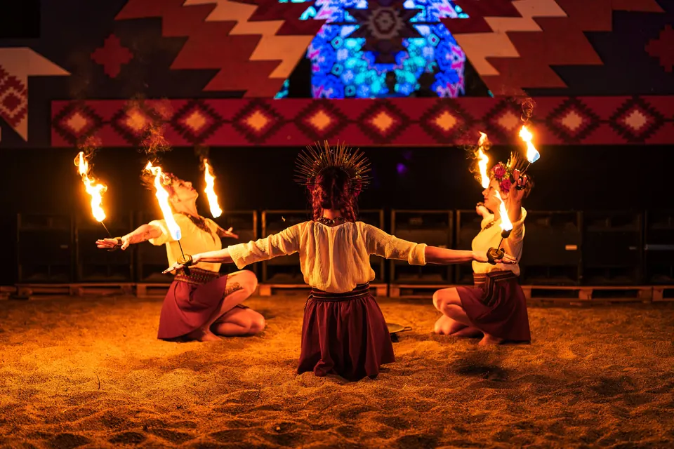 Three fire performers on the sand in front of KOLO
