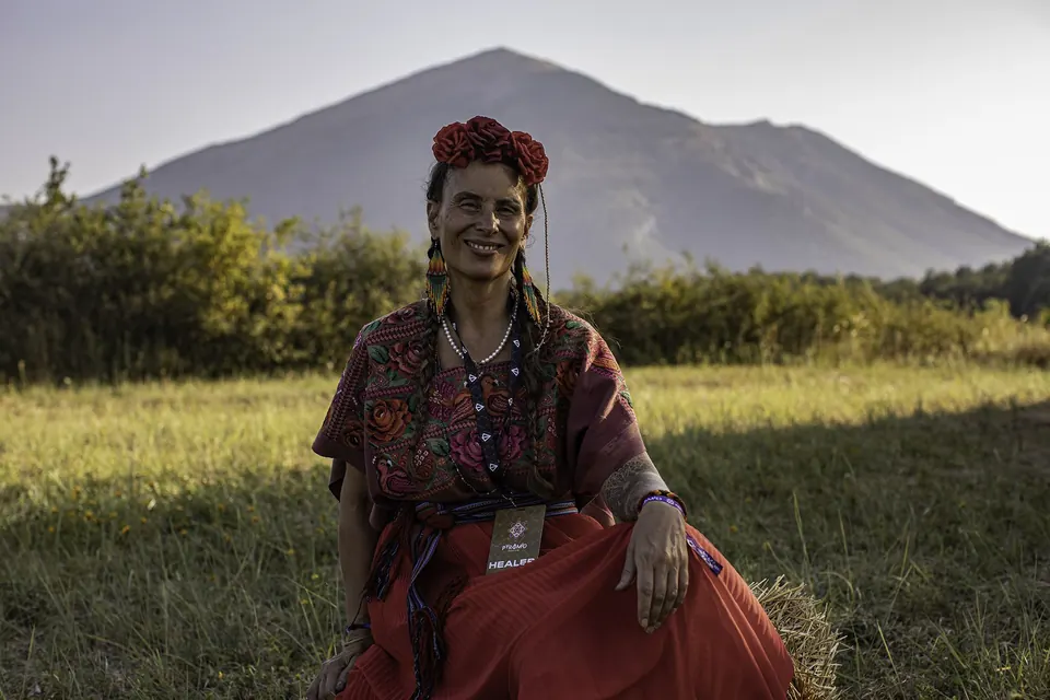 A woman with a flower crown sits in the meadow below Rtanj