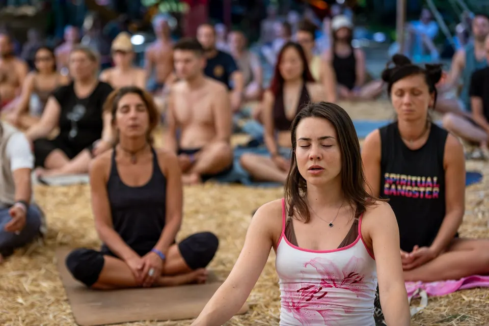 A group meditates cross-legged on the straw