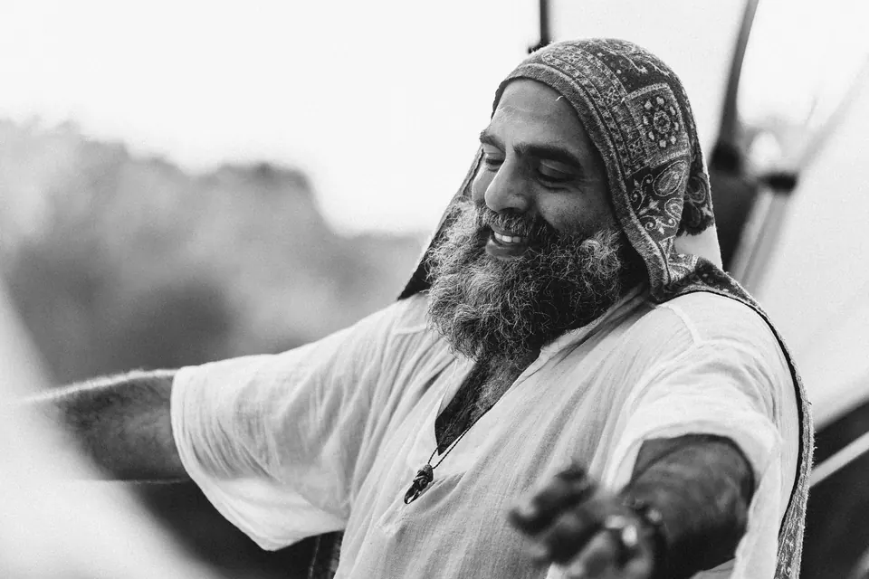 A smiling man with open arms, in black and white