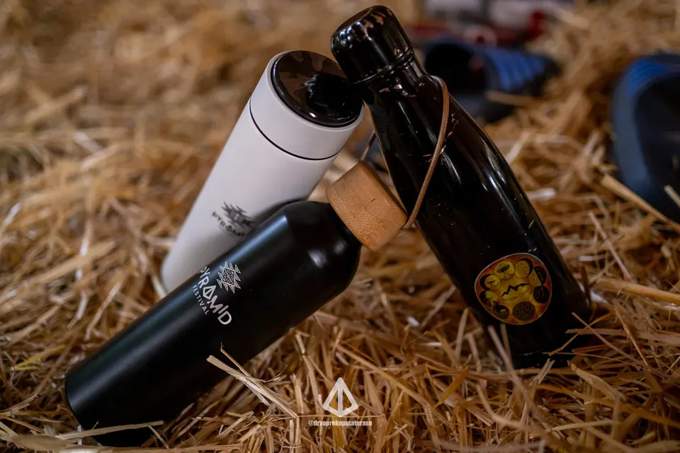 Two reusable Pyramid Festival water bottles lying in straw