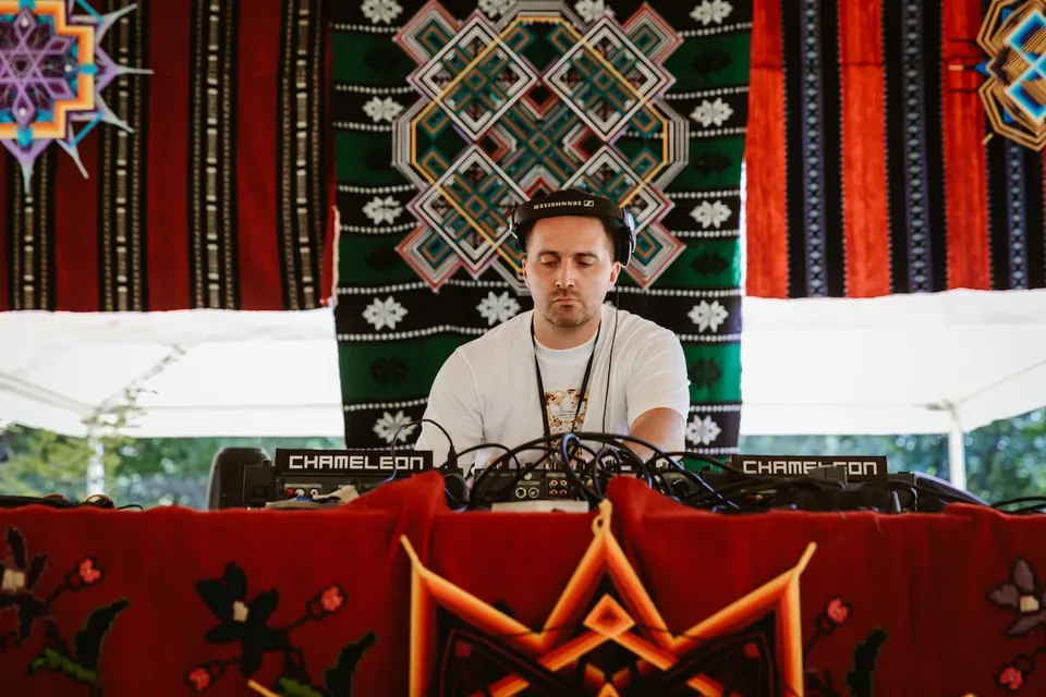 A DJ at the TOK stage in front of a woven backdrop