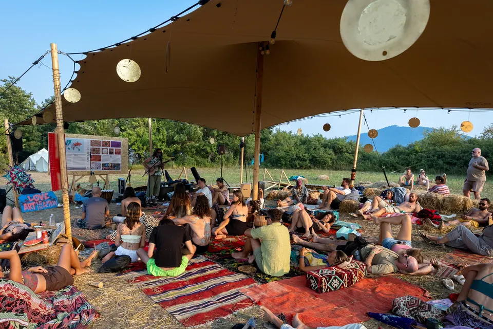 An afternoon audience listening on rugs under the VRELO canopy