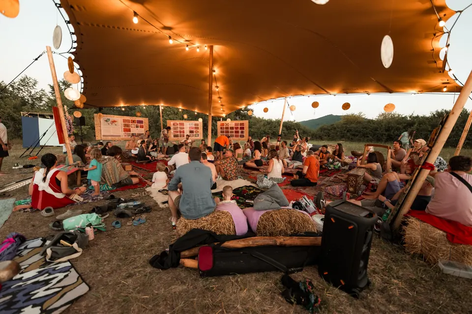 The VRELO jam and art zone tent with string lights and people relaxing on rugs